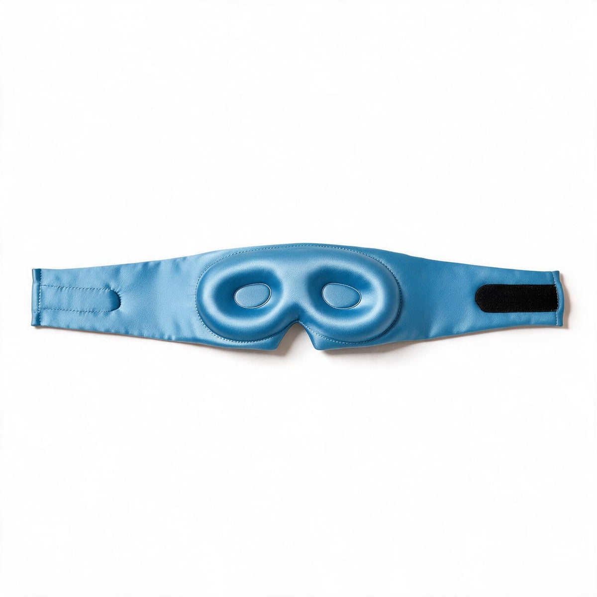 Lunia Reve sleep mask in Sky Blue laid flat, showing the contoured eye cups, the wide band and the adjustable strap fastening